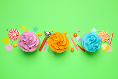 Photo of Flat lay composition with colorful birthday cupcakes on green background