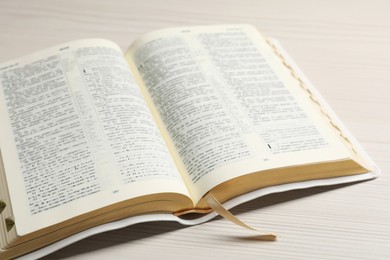 Photo of Open Bible on white wooden table, closeup view. Christian religious book