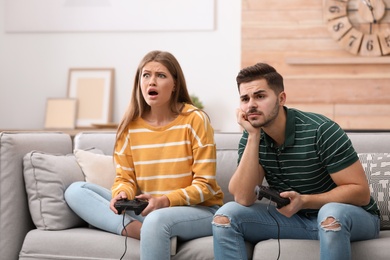 Photo of Emotional young couple playing video games at home