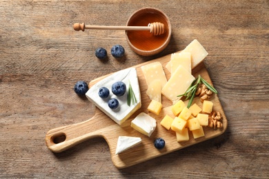 Photo of Flat lay composition with delicious cheeses on wooden table