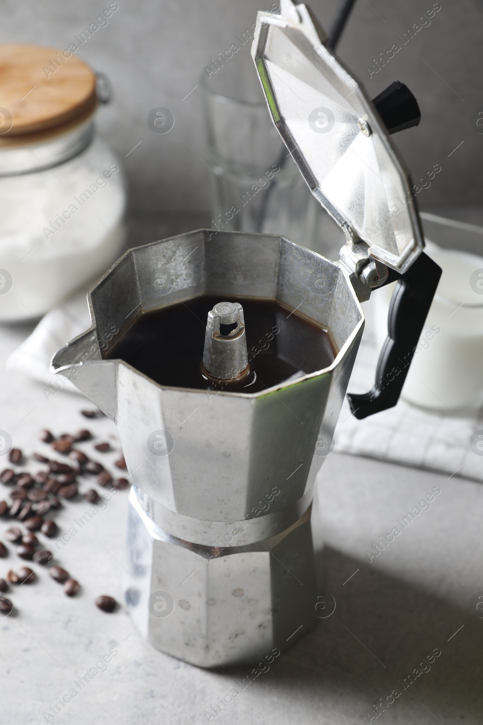 Photo of Brewed coffee in moka pot and beans on light grey table