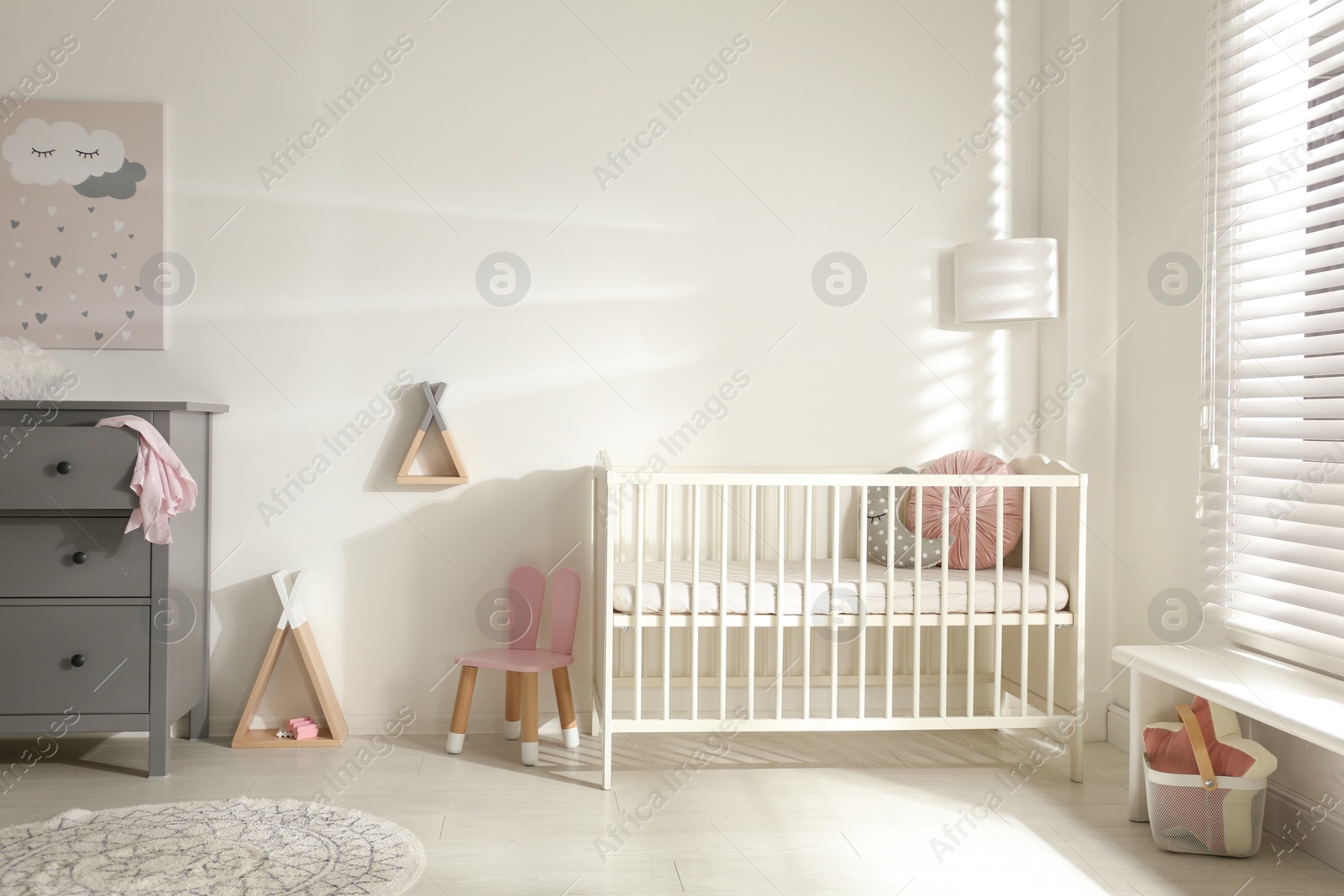 Photo of Cute baby room interior with crib and decor elements