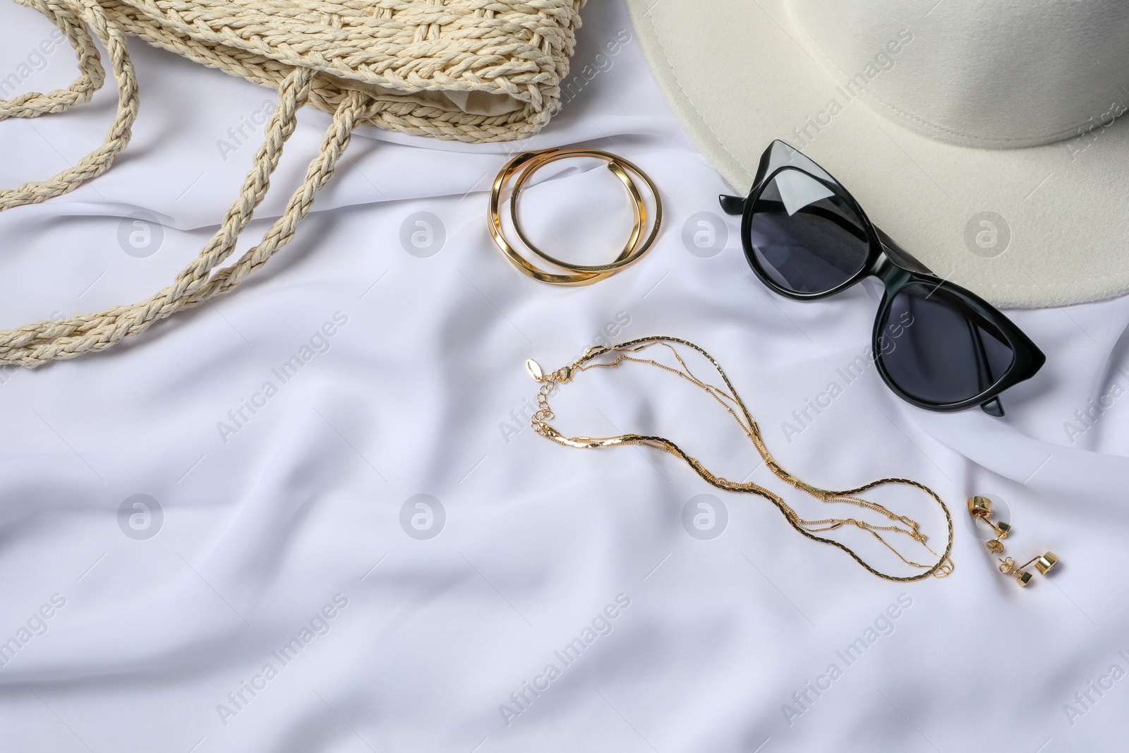 Photo of Elegant bijouterie and accessories on white cloth, above view. Space for text