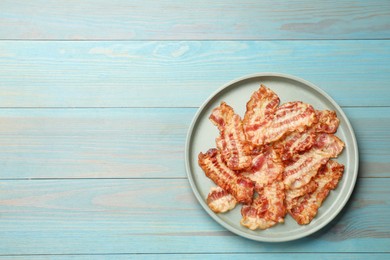 Delicious fried bacon slices on blue wooden table, top view. Space for text