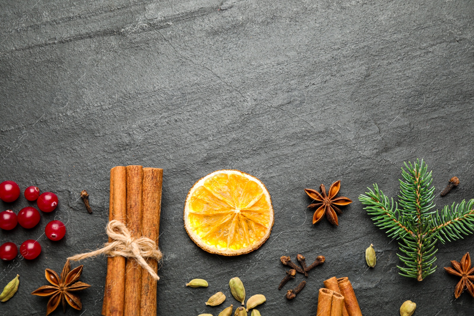 Photo of Flat lay composition with mulled wine ingredients and fir branch on black slate table. Space for text