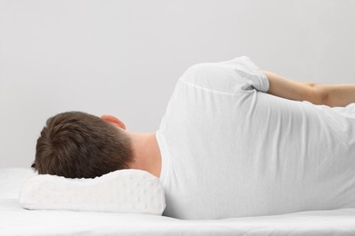 Photo of Man sleeping on orthopedic pillow against light grey background