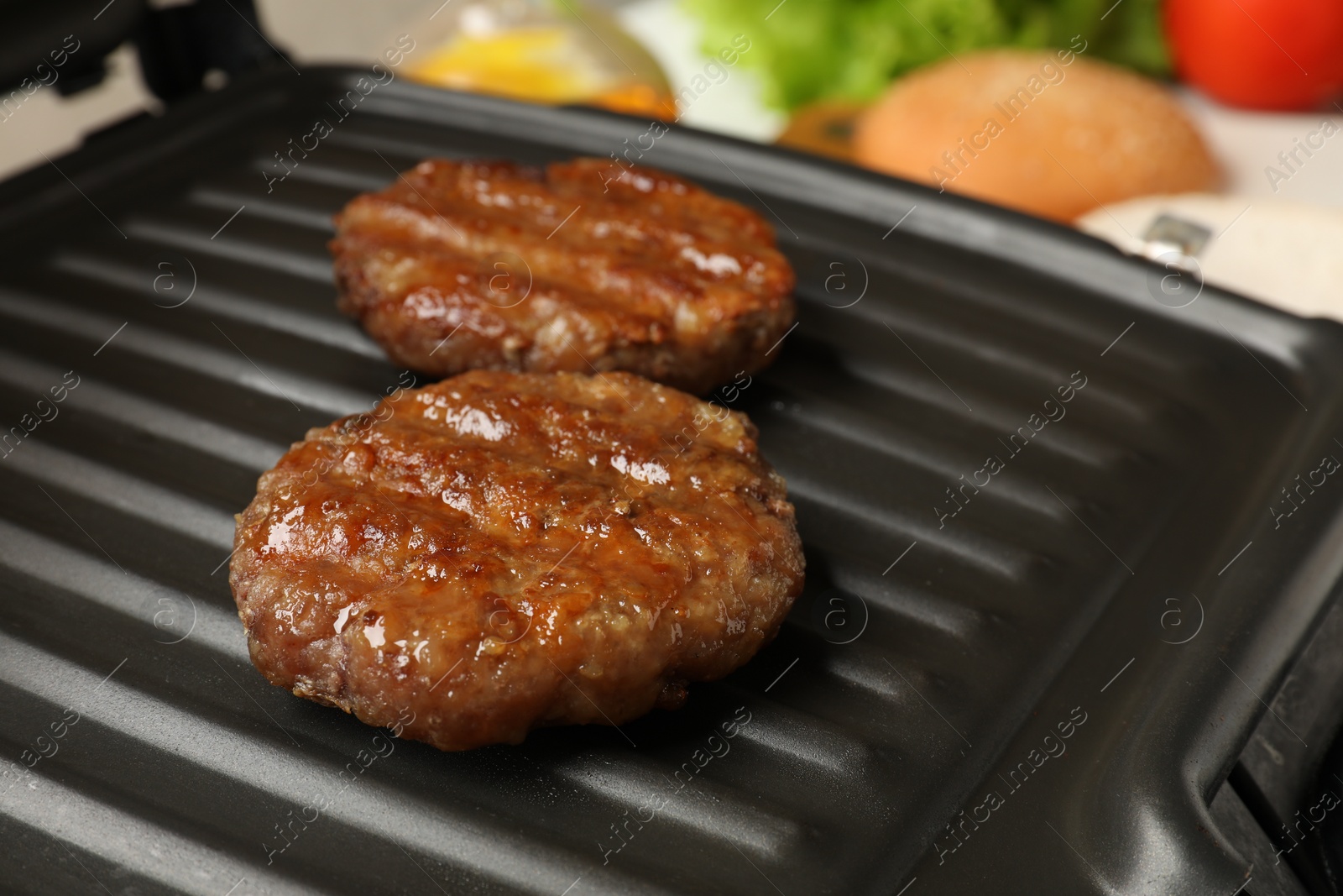 Photo of Delicious hamburger patties on electric grill, closeup