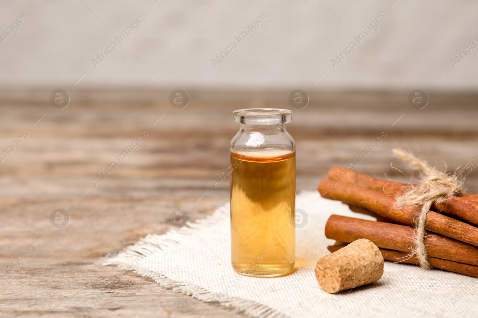 Photo of Bottle with cinnamon essential oil and sticks on wooden table