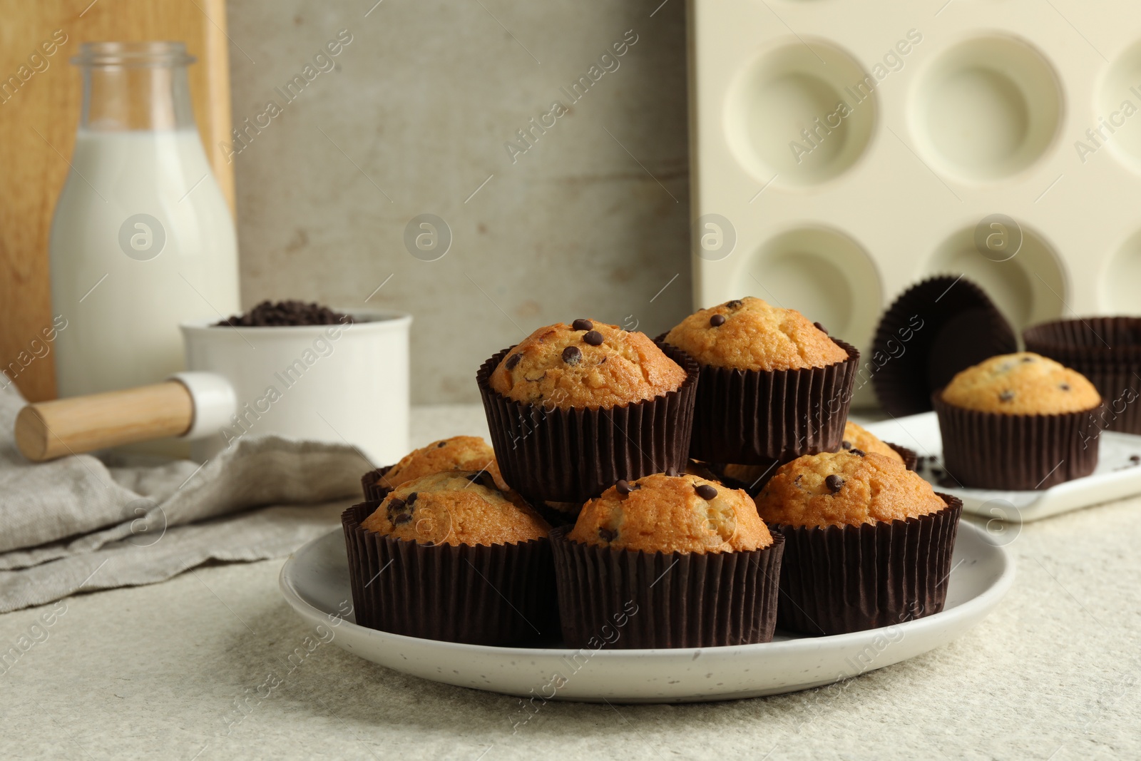 Photo of Delicious sweet muffins with chocolate chips on light textured table