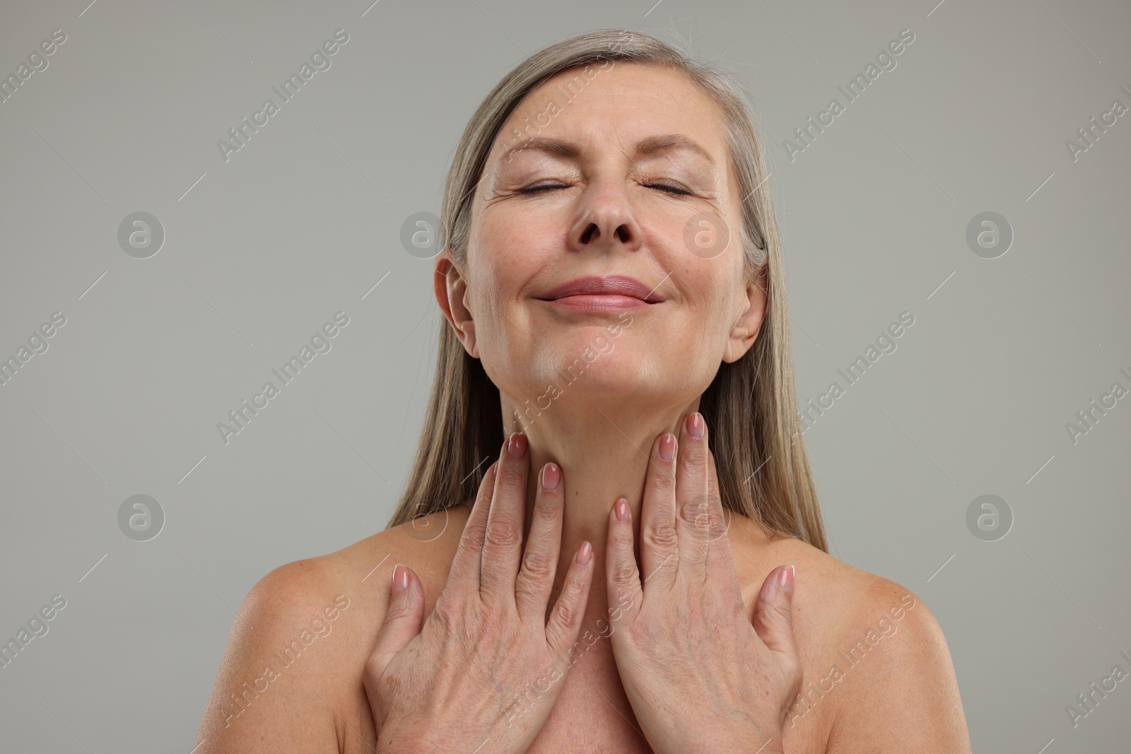 Photo of Beautiful woman touching her neck on grey background