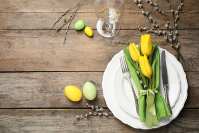 Festive Easter table setting with floral decor on wooden background, flat lay