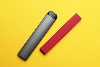 Photo of Different electronic cigarettes on yellow background, flat lay