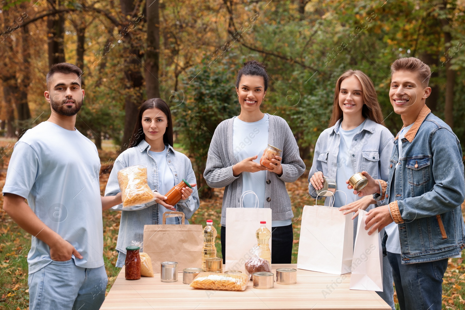 Photo of Portrait of volunteers packing food products at table in park