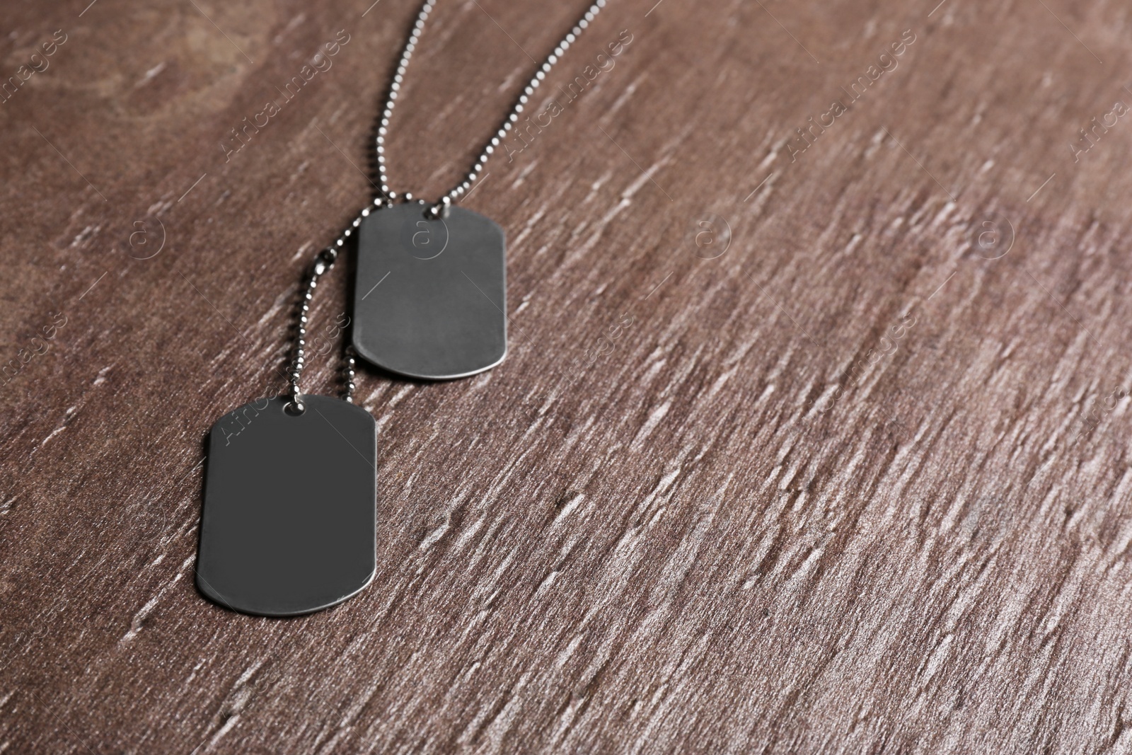 Photo of Blank military ID tags on brown textured background, space for text