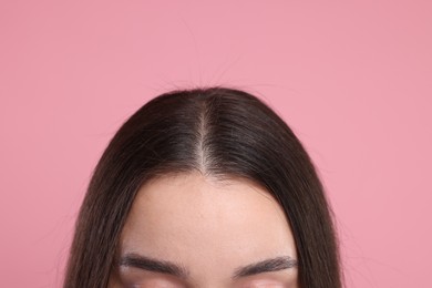 Woman with healthy dark hair on pink background, closeup