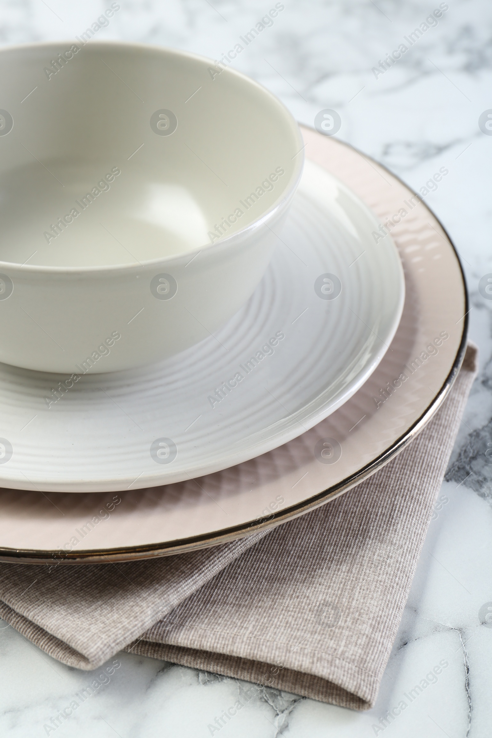 Photo of Clean plates, bowl and napkin on table, closeup