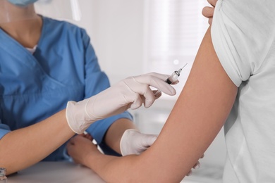 Doctor vaccinating woman against Covid-19 in clinic, closeup