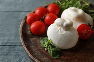 Photo of Delicious burrata cheese with tomatoes on grey wooden table, closeup. Space for text