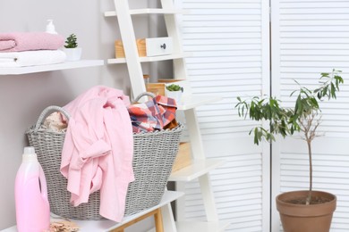 Wicker basket with dirty laundry on table indoors