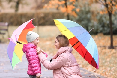 Photo of Mother and daughter with umbrellas in autumn park on rainy day