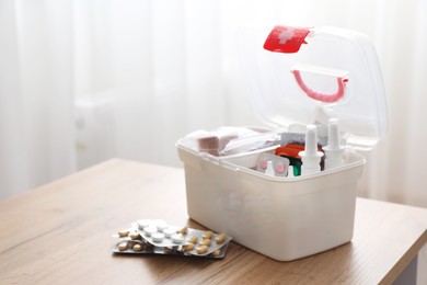 Photo of First aid kit and medicaments on wooden table indoors, closeup. Space for text