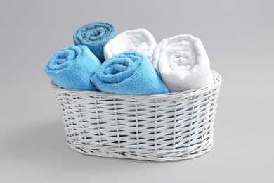 Photo of Basket with soft bath towels on grey background