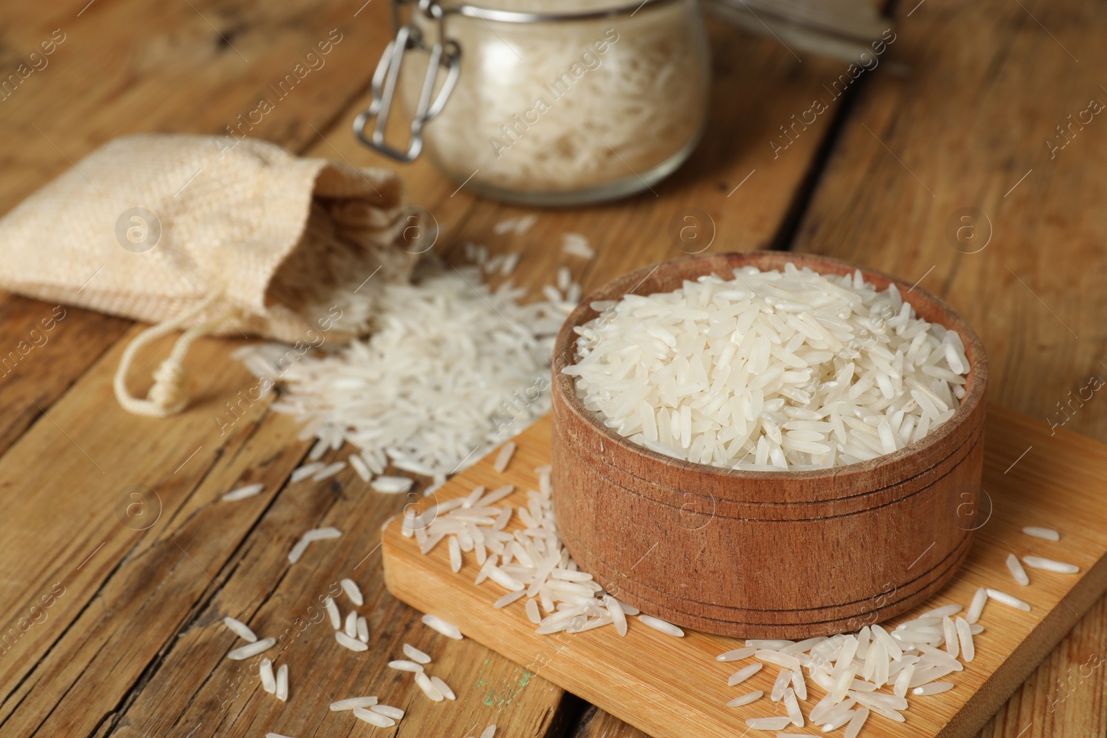 Photo of Raw basmati rice in bowl on wooden table, closeup. Space for text