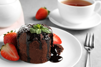 Delicious warm chocolate lava cake with mint and strawberries on table, closeup