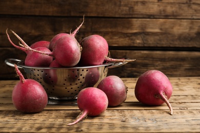 Photo of Raw red turnips on wooden table, closeup