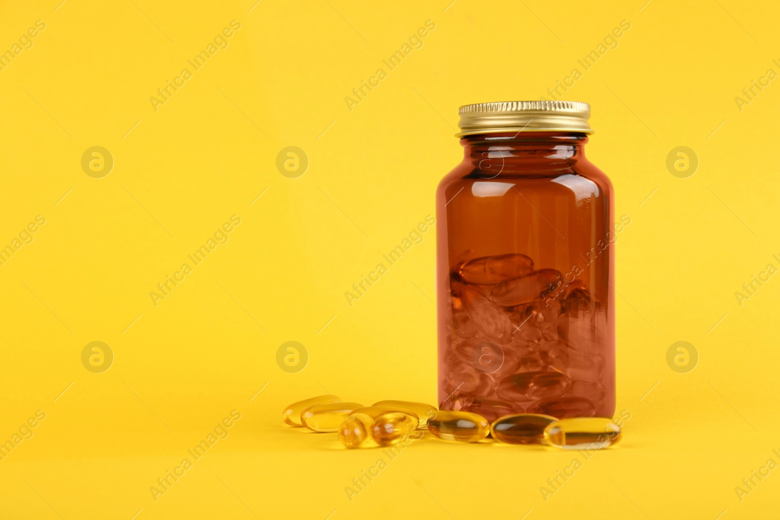 Photo of Jar with vitamin capsules on yellow background, space for text