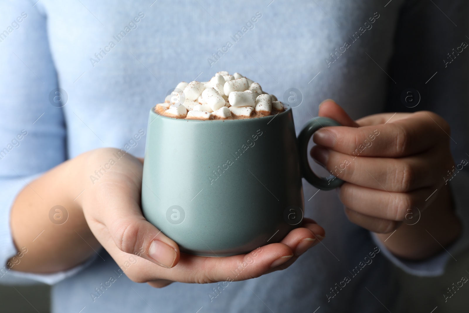 Photo of Woman holding cup of aromatic cocoa with marshmallows, closeup