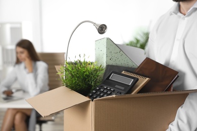 Young man carrying box with stuff in office, closeup