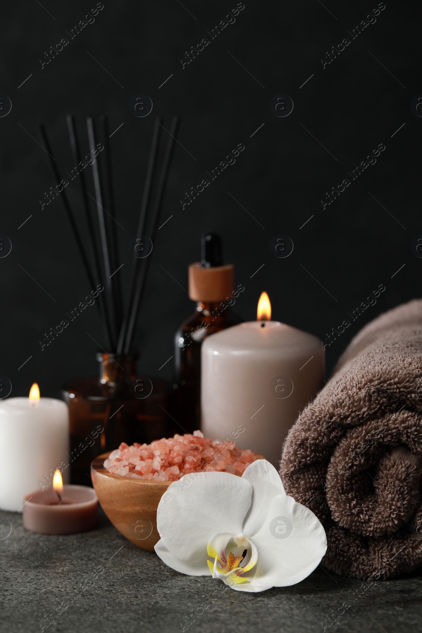 Photo of Beautiful composition with burning candles and different spa products on dark grey table