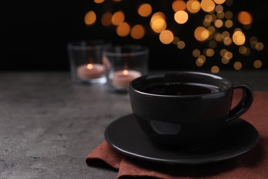 Photo of Cup of hot coffee on dark table against black background, space for text