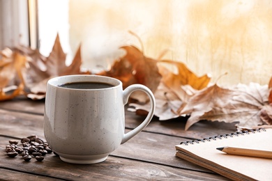 Photo of Composition with cup of hot cozy drink and autumn leaves on windowsill. Space for text