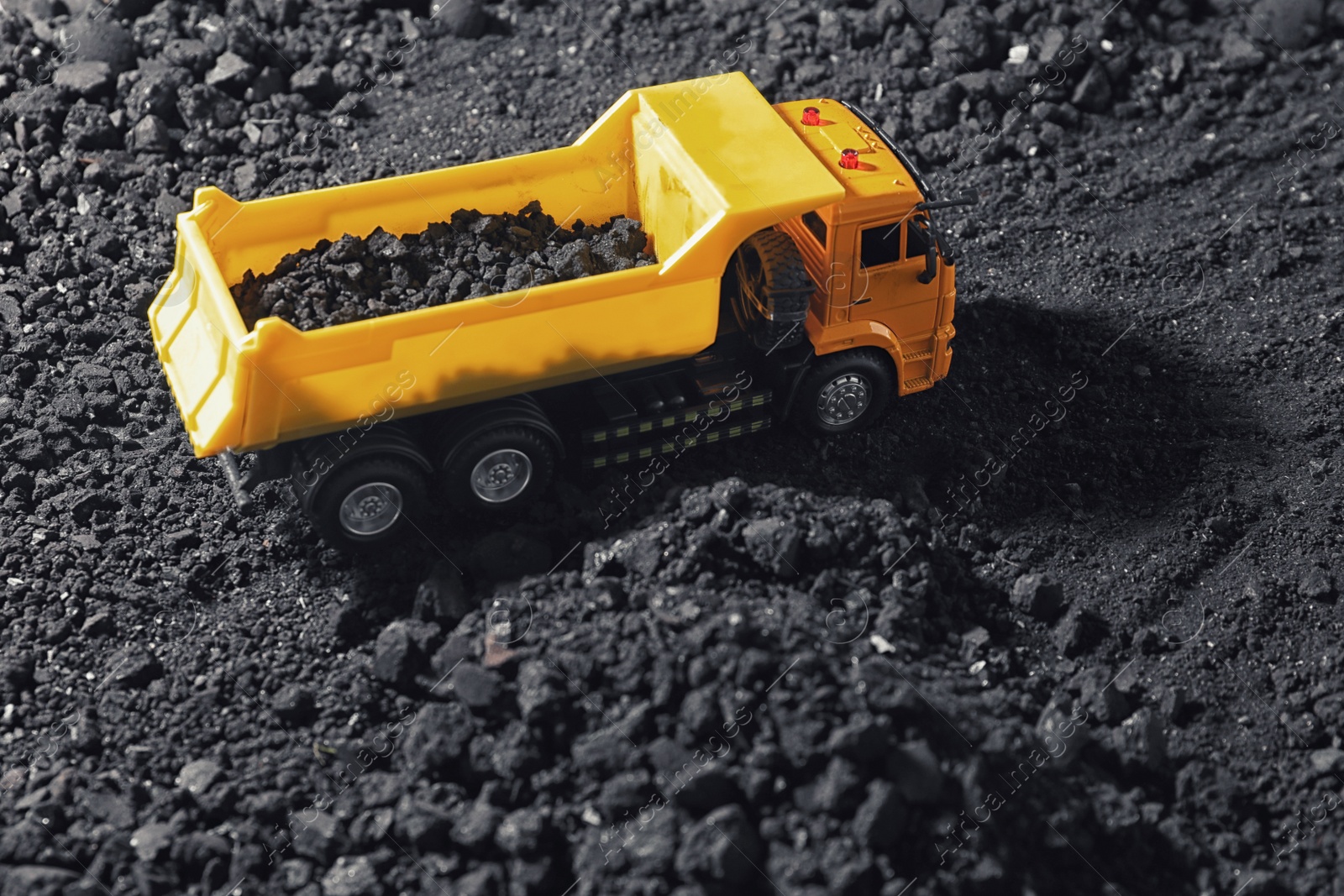 Image of Toy tipper truck with coal in field