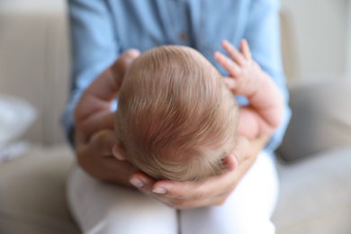 Mother holding her newborn baby at home, closeup