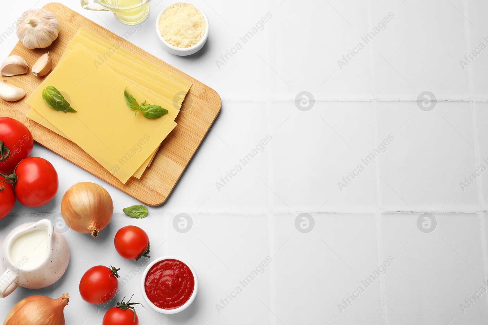 Photo of Ingredients for lasagna on white tiled table, flat lay. Space for text