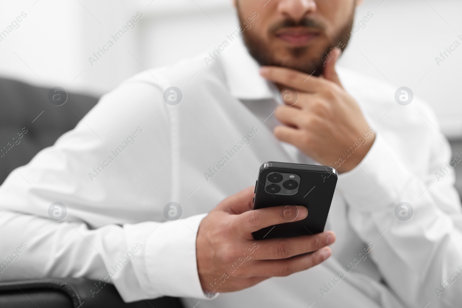 Photo of Young man using smartphone indoors, selective focus