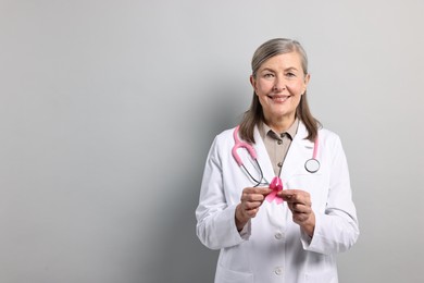 Photo of Mammologist with pink ribbon on gray background, space for text. Breast cancer awareness