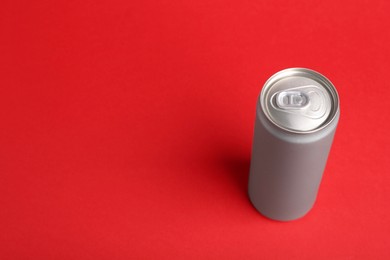 Photo of Energy drink in can on red background, space for text