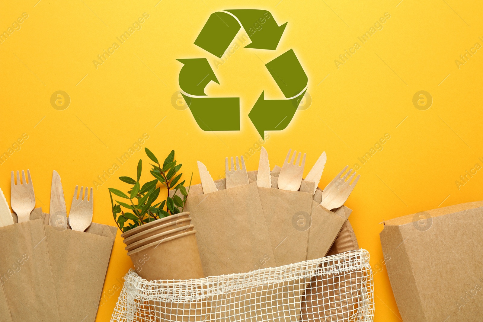 Image of Flat lay composition with eco friendly tableware and recycling symbol on yellow background