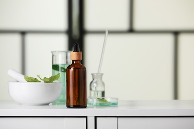 Photo of Bottle and glass tubes with leaves on white lab drawer indoors, space for text