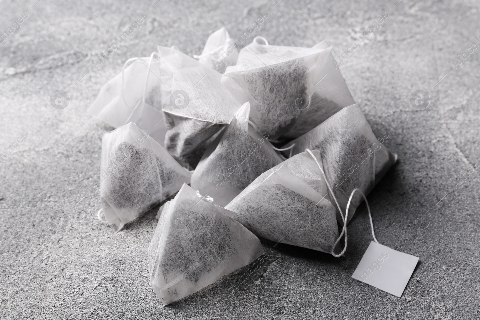 Photo of Tea bags with tabs on light grey table, closeup