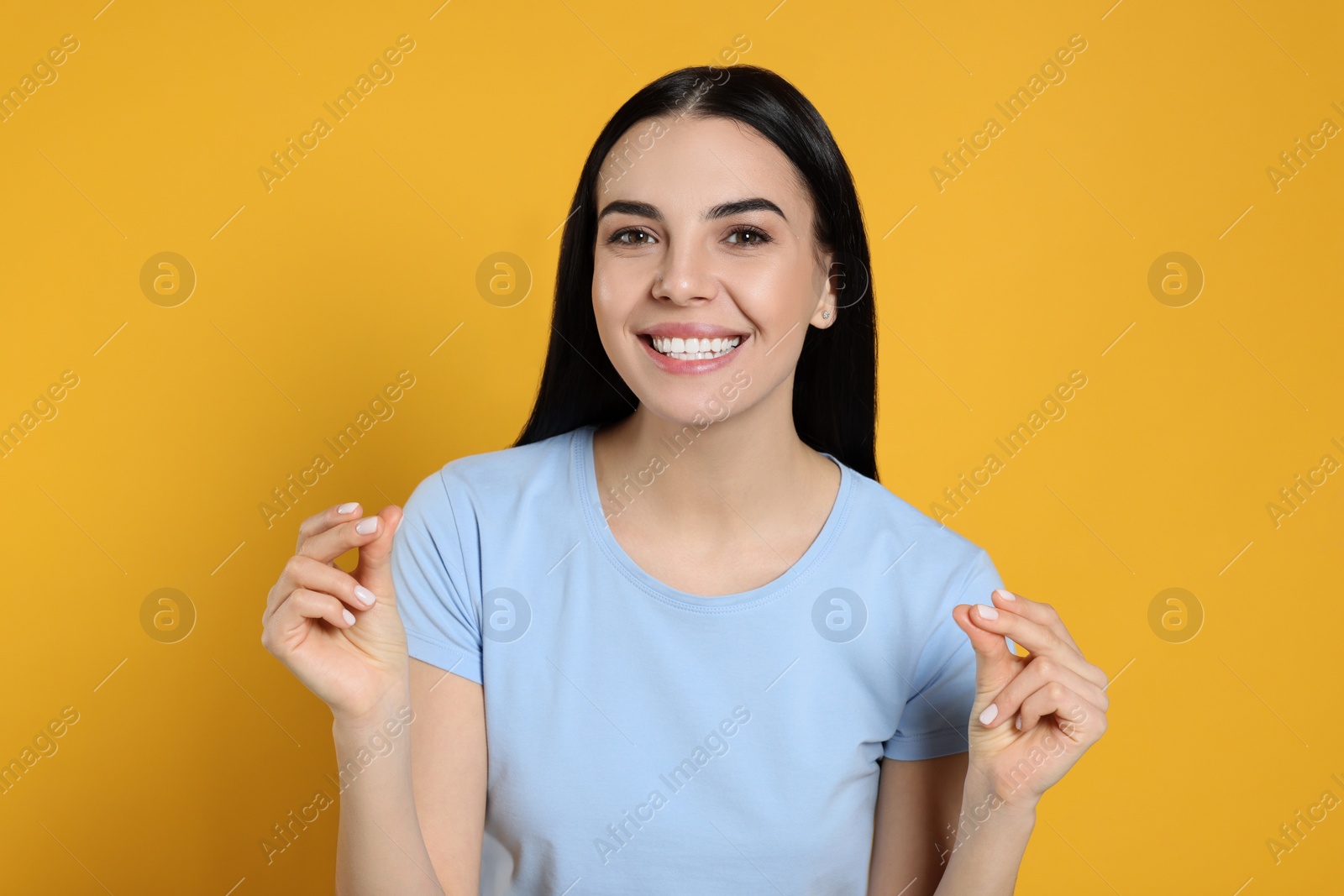 Photo of Young woman snapping fingers on yellow background