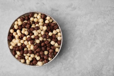 Photo of Tasty cereal balls in bowl on grey table, top view. Space for text