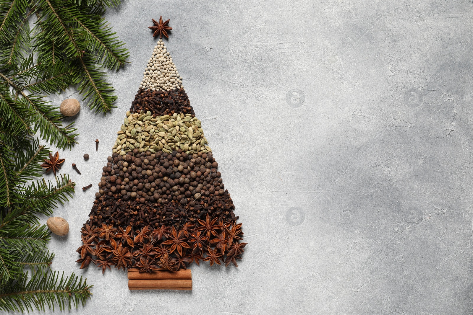 Photo of Christmas tree made of different spices and fir branches on gray textured table, flat lay. Space for text