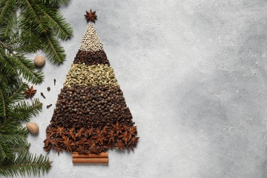 Christmas tree made of different spices and fir branches on gray textured table, flat lay. Space for text