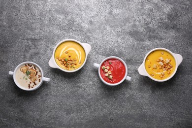 Different tasty cream soups on grey table, flat lay