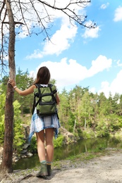 Young woman with backpack in wilderness. Camping season